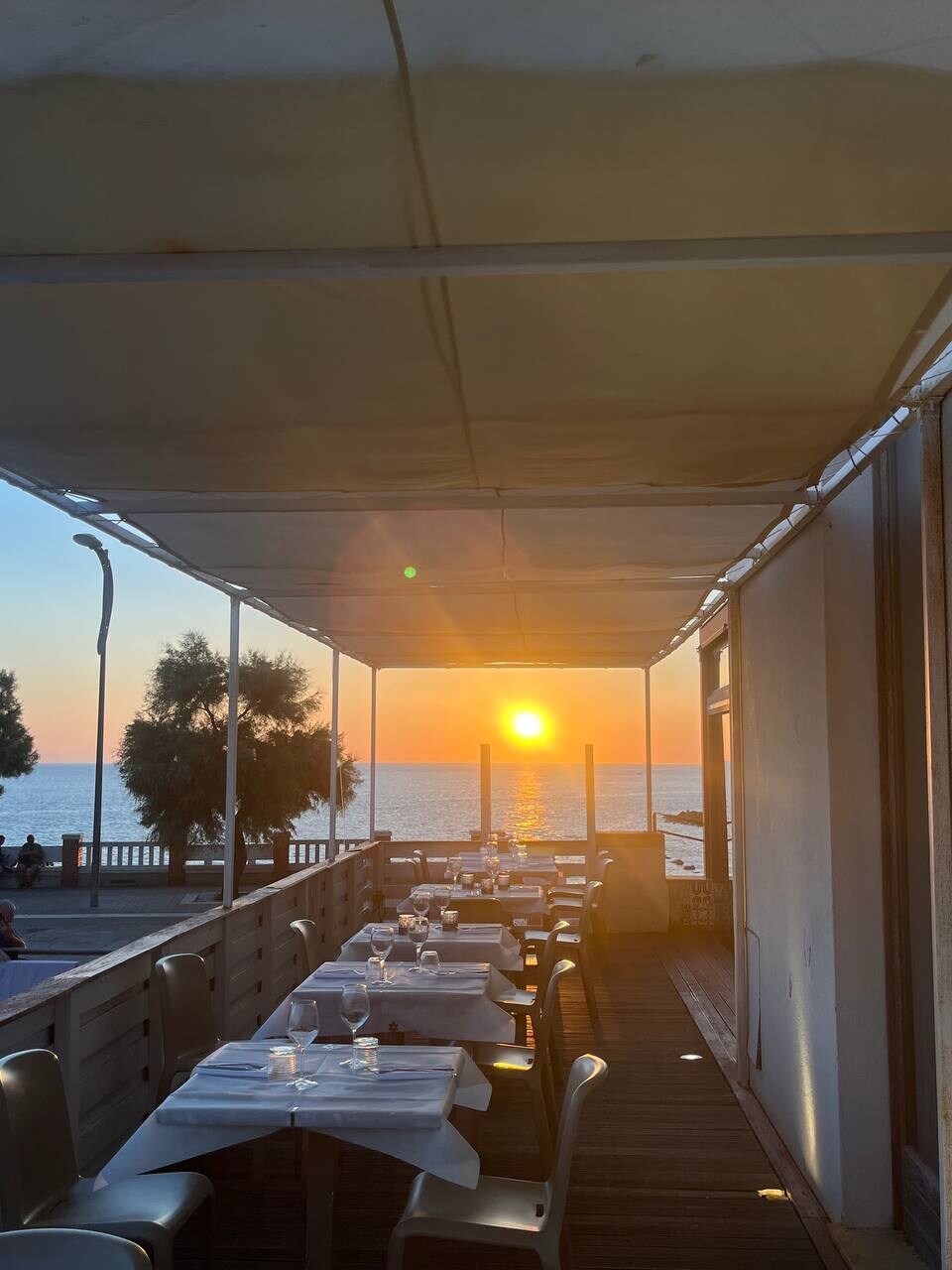 Tavoli sulla terrazza de La Rocchetta davanti al tramonto sul mare